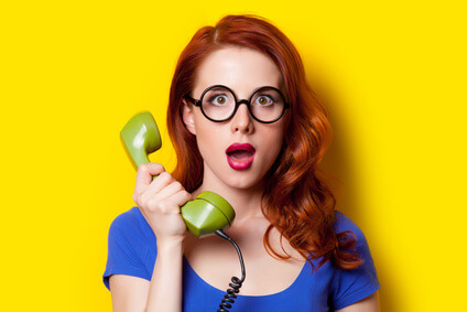 beautiful surprised young woman with retro phone on the wonderful yellow background